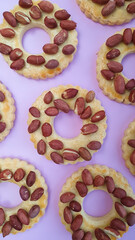 Round flower peanut cookies on violet background flat lay pattern