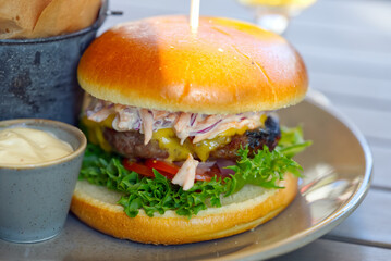 home made burger with fried potatoes and souce on wooden table close up