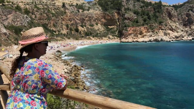 Young woman in hat from a viewpoint looking Moraig  beach in Alicante