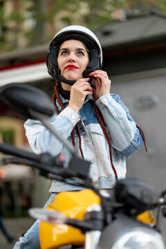 Frontal shot of a young woman fastening a motorcycle protective helmet