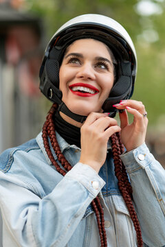 Close-up of a young woman fastening a motorcycle protective helmet