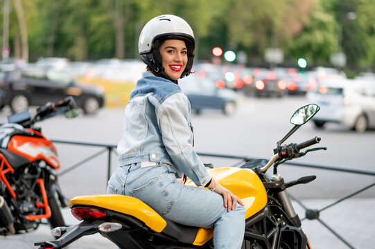 Right side shot of a young woman riding a yellow motorcycle