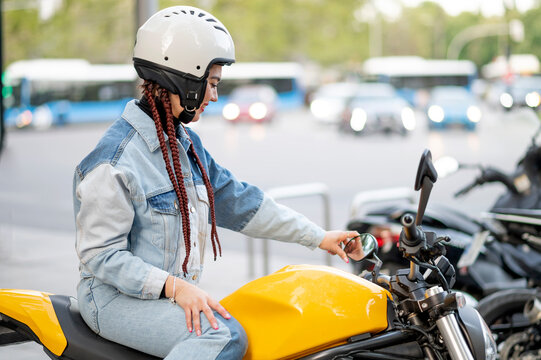 Right side shot of a young woman riding a yellow motorcycle
