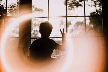 Back of Young Boy in Window Making Peace Sign With Circle Light Effect
