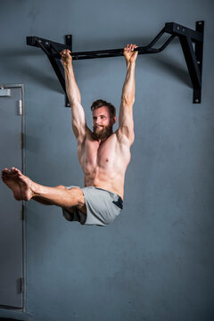 man with beard hanging on pull up bar at gym in Bangkok