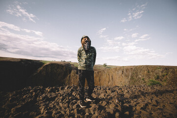 Boy in Camouflage Hoodie and Bandit mask Stands on Basalt Mesa