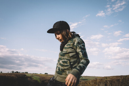 Boy in Camouflage Hoodie Stands Against the Open Sky
