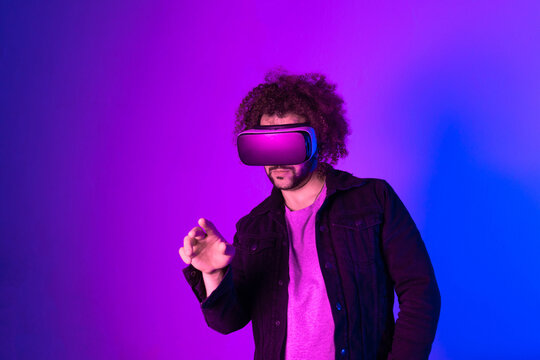 Hipster young man using virtual reality headset over blue purple