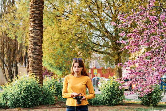 Young girl walking in the park with a photo camera in spring