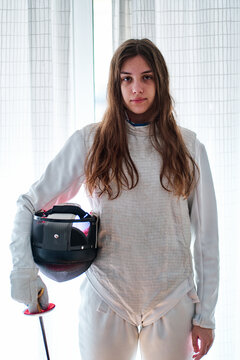 Portrait of a young fencer girl with mask and foil in hand