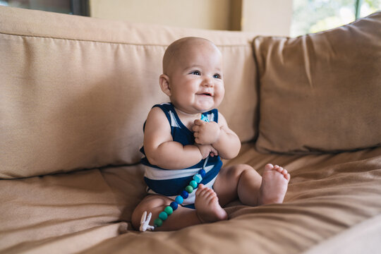 Cute Baby Sitting On Couch with a toy