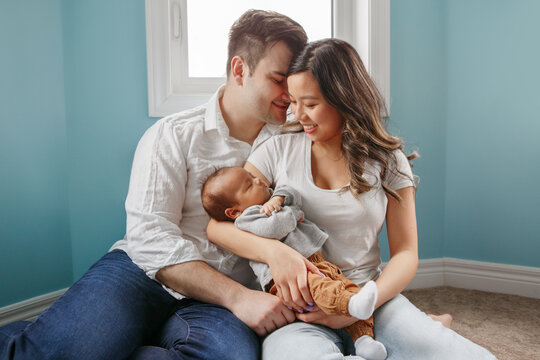 Young family with newborn baby boy at home. Happy parents with kid
