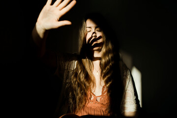 A woman holding up her hand to light casting a shadow on her face