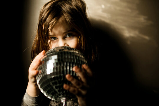 Young girl wearing a leopard pajamas holding a disco ball