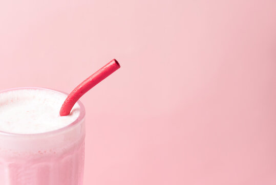 Raspberry milkshake with a reusable eco-friendly metal straw. Close up view.