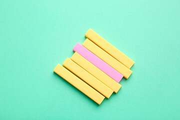 Pink eraser among yellow ones on color background. Concept of uniqueness