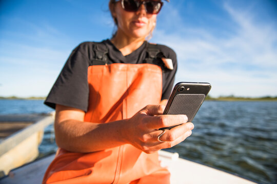 Woman with phone working on the water in aquaculture oyster farm