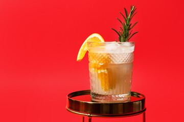 Glass of tasty orange cocktail with rosemary on color background
