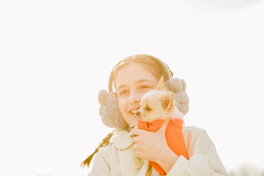 Portrait of a happy teenage girl with her small chihuahua dog. A girl on the background of nature hugs her Chihuahua dog in clothes.