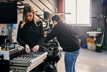 A woman and a man are working together in a mechanic shop
