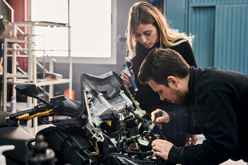 A woman and a man are working together in a mechanic shop