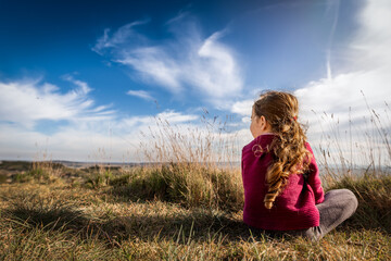 Girl sits in sunshine with back to camera in south of France in summer