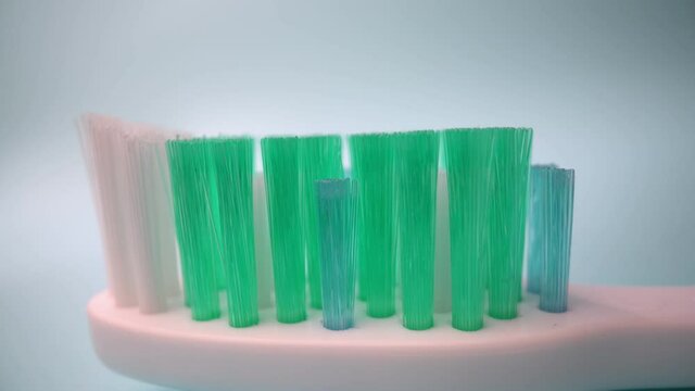 Extreme macro video filming, toothbrush on a blue background in motion, Applying toothpaste to the brush.. Close-up.