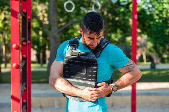 Dark-haired Man With Beard Adjusting A Weight Vest In A Fitness Park. Outdoor Fitness Concept.