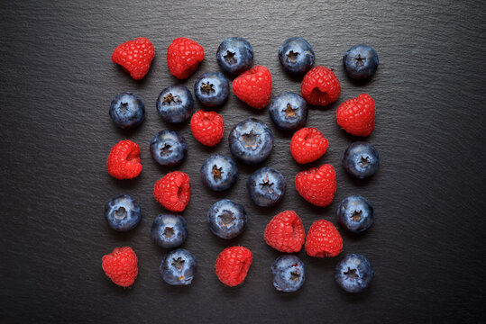 Raspberries and blueberries on a slate table.