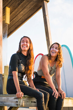 Two women friends smiling before a sunrise summer surf