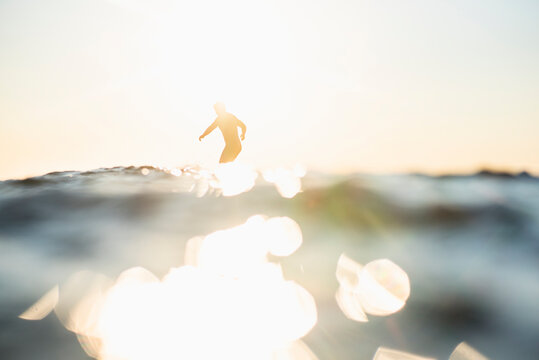 Backlit Man Surfing a wave during summer sunset
