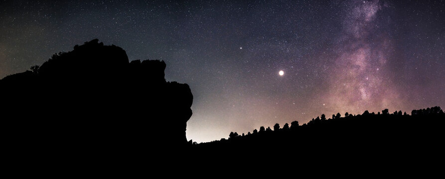 The silhouette of a face sculpted in the mountain, milky way
