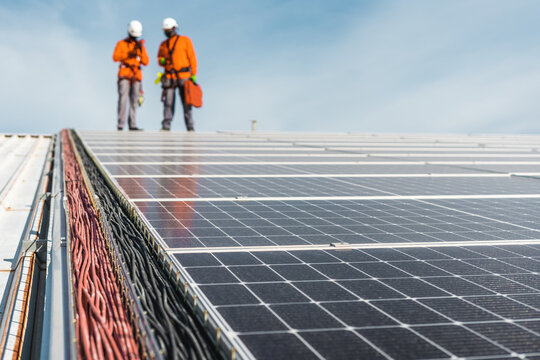 Solar panel installation with unrecognizable technicians on top