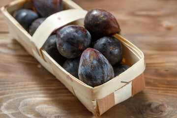 Ripe figs in a wicker basket on a wooden background.