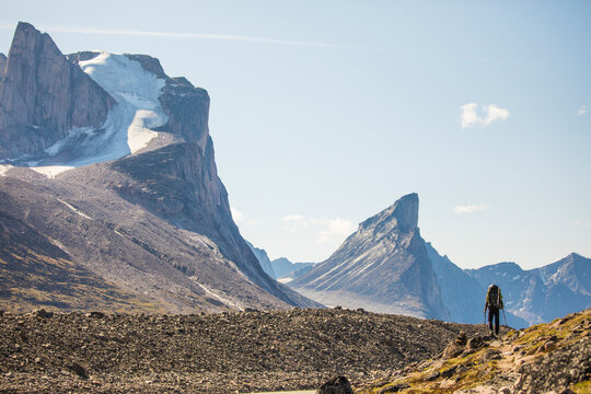 Rear view of backpacker hiking below mountain range, Mt. Thor