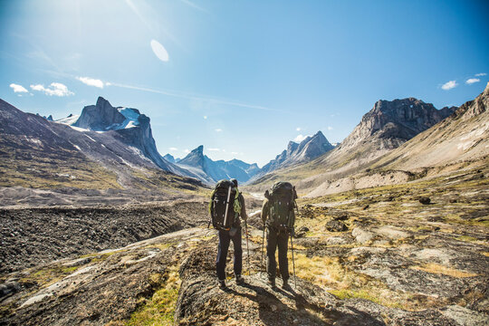 Two backpackers look down Akshayak Pass, toward Mount Thor.