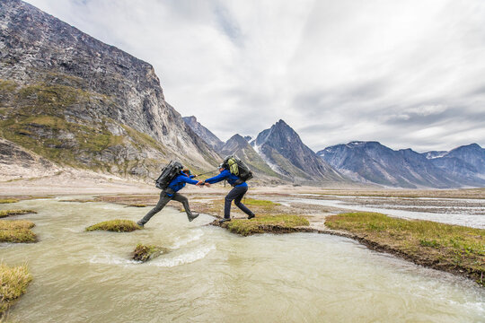 Backpackers work together to cross a river channel.