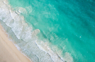 Aerial shot of the bright turquoise Hawaii ocean meeting the shore