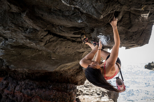 Gutsy athlete courageously hanging from an enormous rock at The Arch