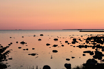 Fototapeta na wymiar Azure water with stones of a Baltic sea on a sunset