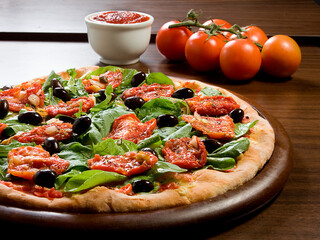 Pizza de tomate seco com rúcula e azeitonas pretas e mussarela em fundo de mesa de madeira com ingredientes.