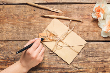 Woman with envelope writing text LAVENDER LAVANDULA on wooden background