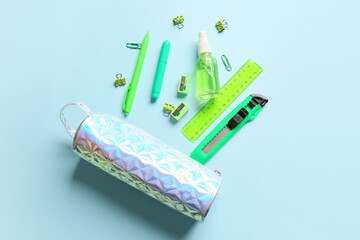 Pencil case, stationery and bottle of sanitizer on blue background