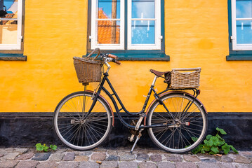 Fototapeta na wymiar Bicycle parked near yellow wall of an old house in a classical traditional European village.