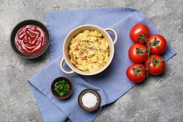 Pot of tasty chicken curry and ingredients on grunge background