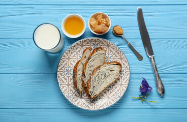 Plate with tasty poppy seed bun, glass of milk, honey and succade on color wooden background