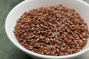 Bowl with flax seeds on table, closeup