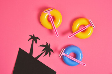 pink disposable razors on small toy balloons, black cardboard palms, body hair removal before beach vacation