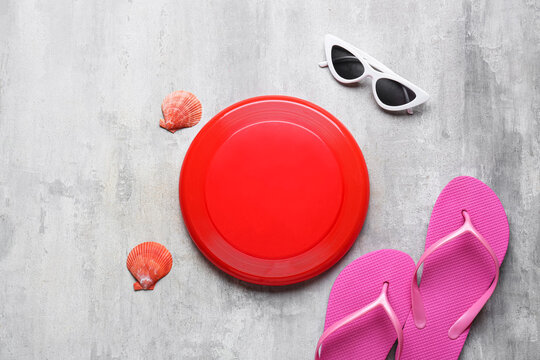 Frisbee disk, sunglasses and flip-flops on grunge background