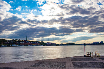 Fototapeta premium Rays of Sunlight Break through the Clouds and Shine on the Waterfront in Stockholm, Sweden